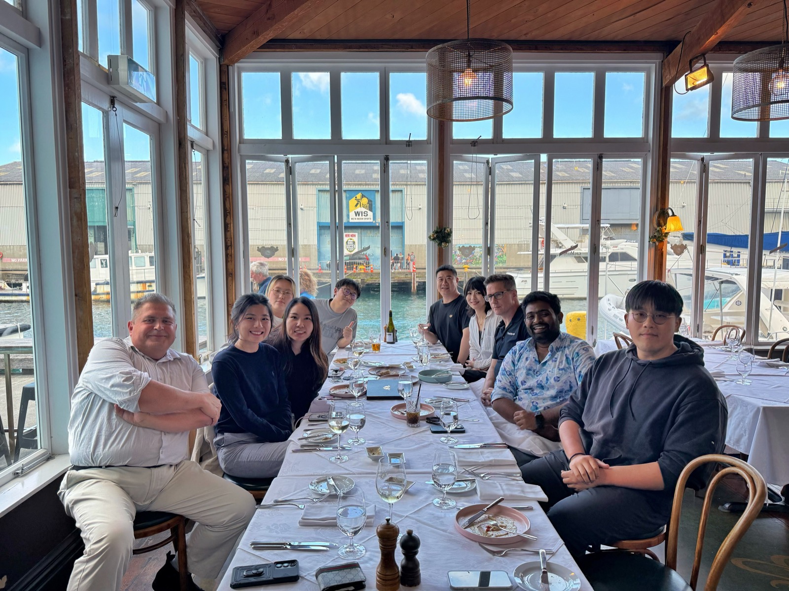 The TTAP team gathered around a long table at a Wellington waterfront restaurant, harbour visible through the windows behind.